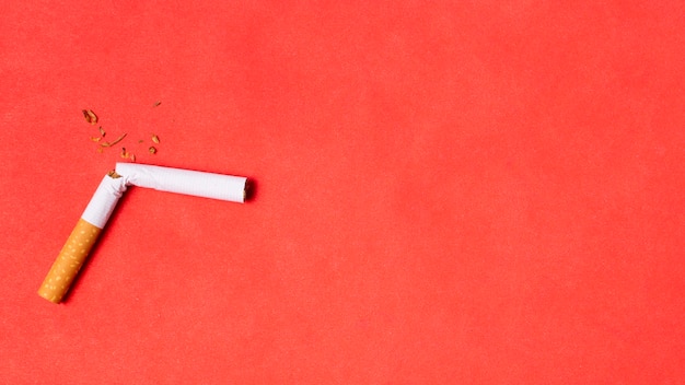 Free photo broken cigarette on red background