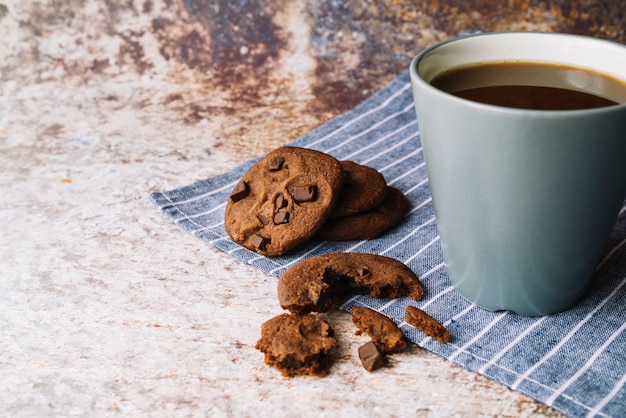 Broken cookies with cup of coffee on rustic backdrop