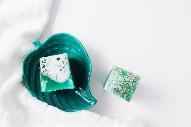 Free Photo broken soap in the leaf bowl with napkin on white background