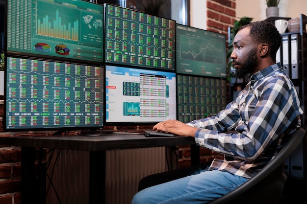 Free photo brokerage company employee sitting at multi monitor workstation while trading risk free assets. investment company trader using forex exchange platform and real time statistics to predict market trend