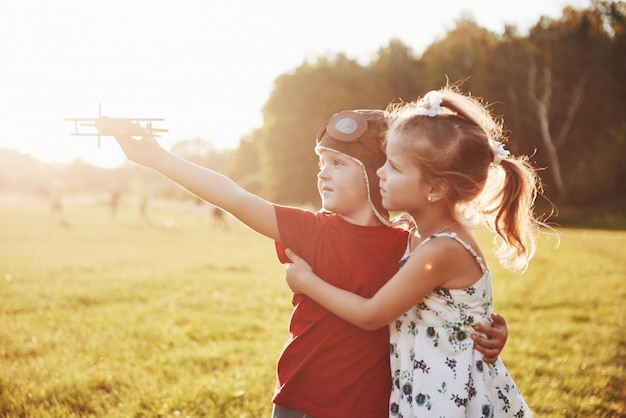 Free Photo brother and sister are playing together. two children playing with a wooden airplane outdoor