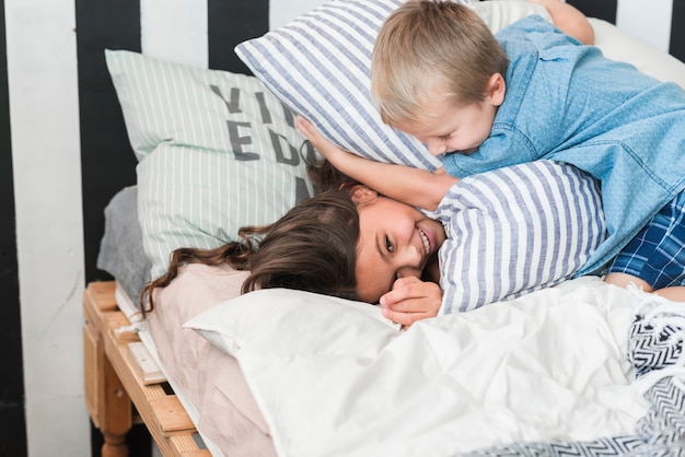 Free photo brother and sister playing with pillows on bed