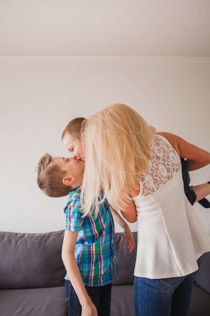 Brothers kissing next to their mother