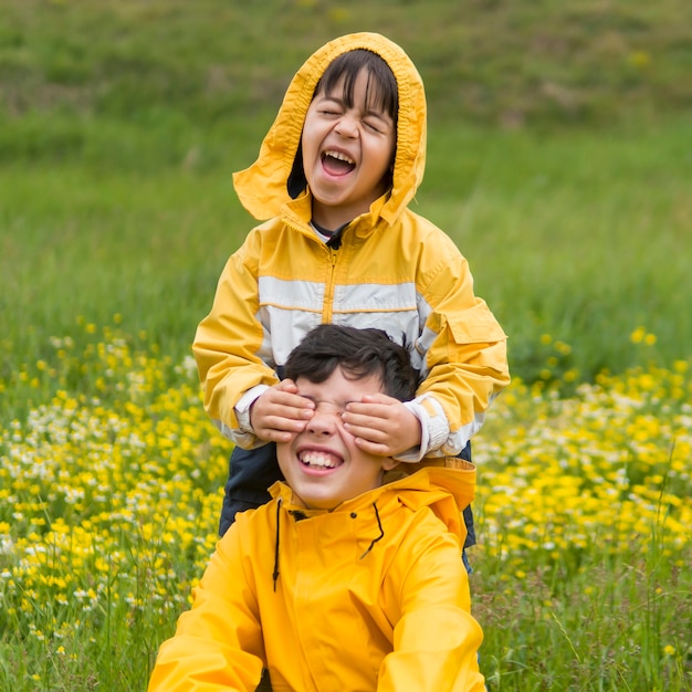 Brothers in raincoat playing in the park