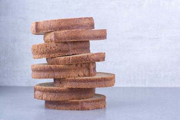 Brown bread slices stacked up on marble surface