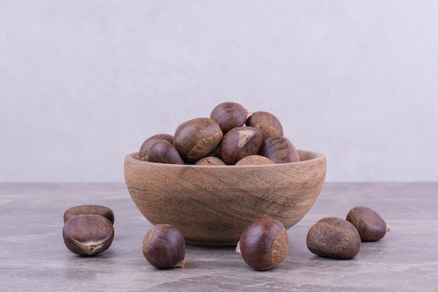 Brown chestnuts in a wooden cup on the stone