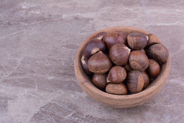 Brown chestnuts in a wooden cup on the stone