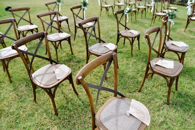 Free Photo brown chiavari chairs and hand fans outdoors on the grass