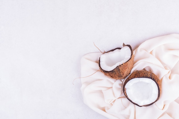 Free Photo a brown coconut cut into two pieces on a white towel