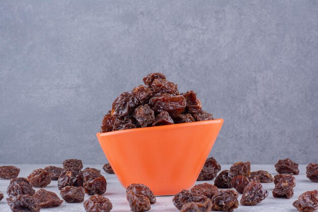 Brown dried cherries inside a dish on concrete background. High quality photo