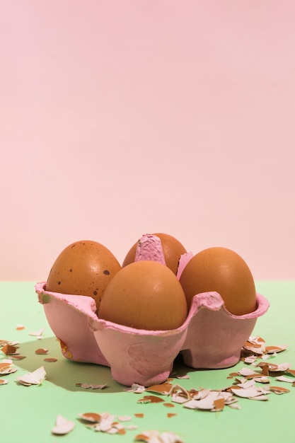 Free photo brown eggs in rack with broken shell on green table