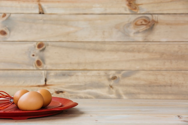 Brown eggs with whisk on plate