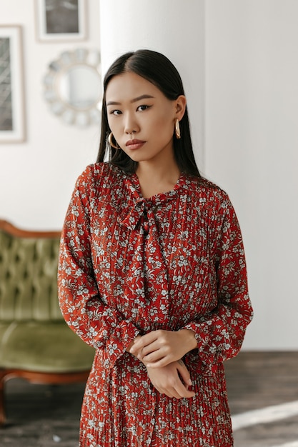 Free photo brown-eyed brunette woman in floral red dress looks at front