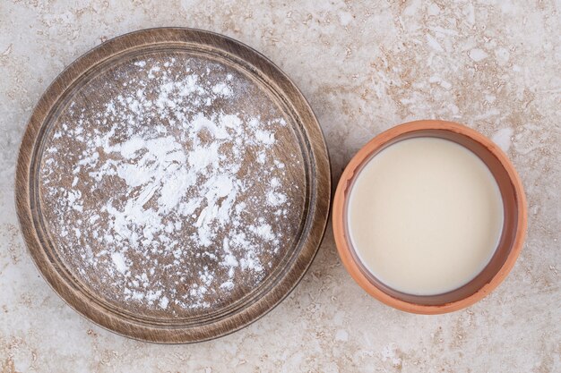 A brown plate of flour and a clay bowl