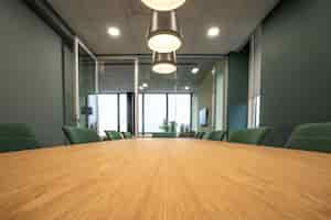 Free photo brown table surrounded with green chairs under lamps in a room