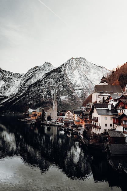 Brown and white concrete houses near body of water and mountain