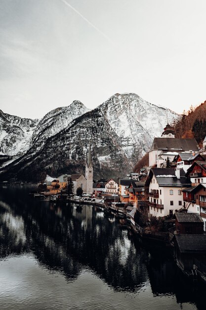 Brown and white concrete houses near body of water and mountain