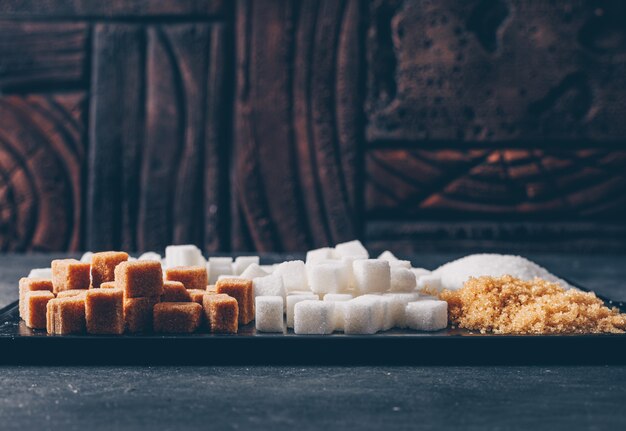 Brown and white sugar in a cutting board. side view.