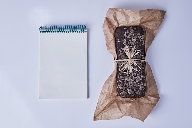 Free Photo brownie pie on a piece of paper with a recipe book aside.