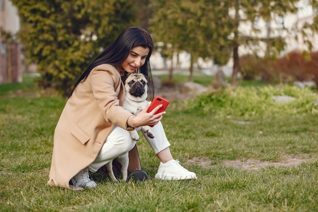 Brunette in a brown coat walks with pug