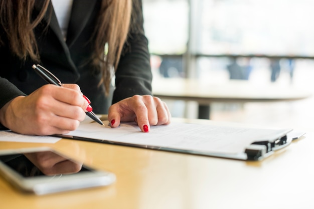 Free photo brunette businesswoman writing on a document