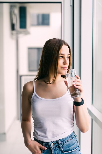 Brunette drinking water in the living room at home