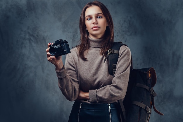 Free photo a brunette female traveler with backpack holds compact photo camera.