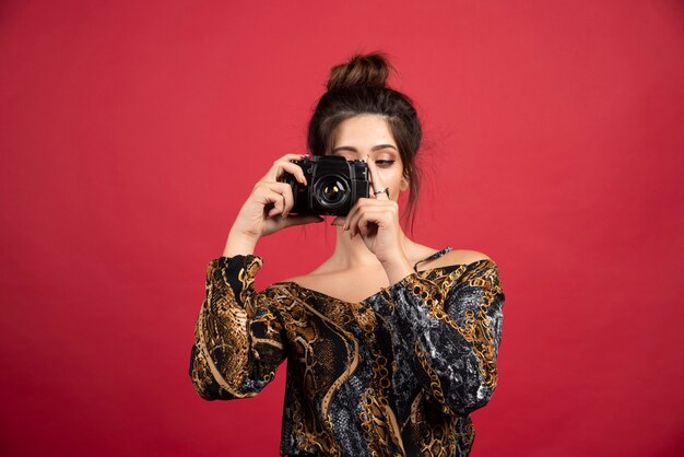 Brunette girl holding a professional dslr camera and doing photosession.