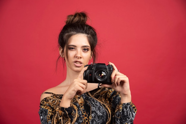 Brunette girl holding a professional dslr camera and doing photosession.