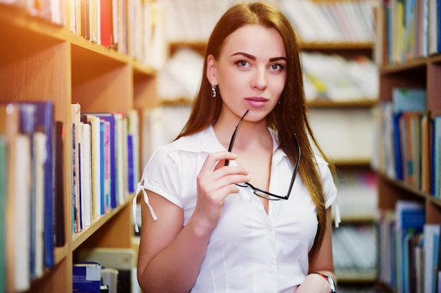 Brunette girl at library with glasses on hand wear on white blouse and black mini skirt Sexy business woman or teacher concept