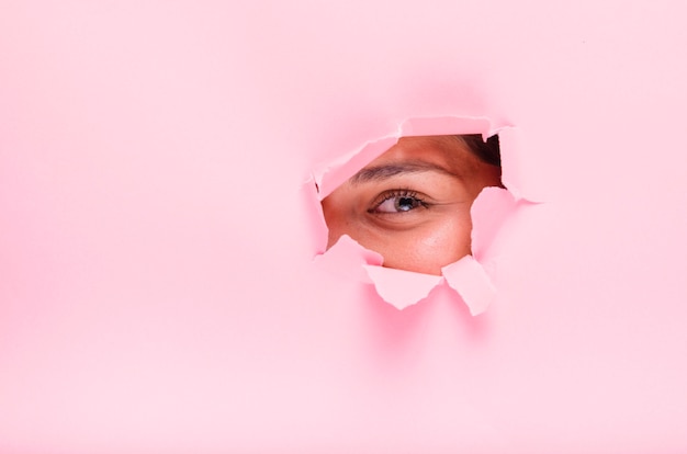 Brunette girl posing through a paper hole