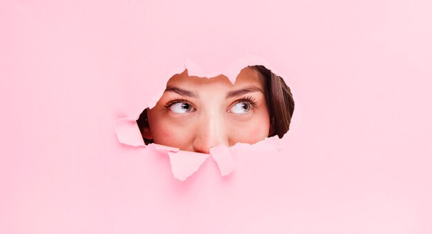 Brunette girl posing through a paper hole