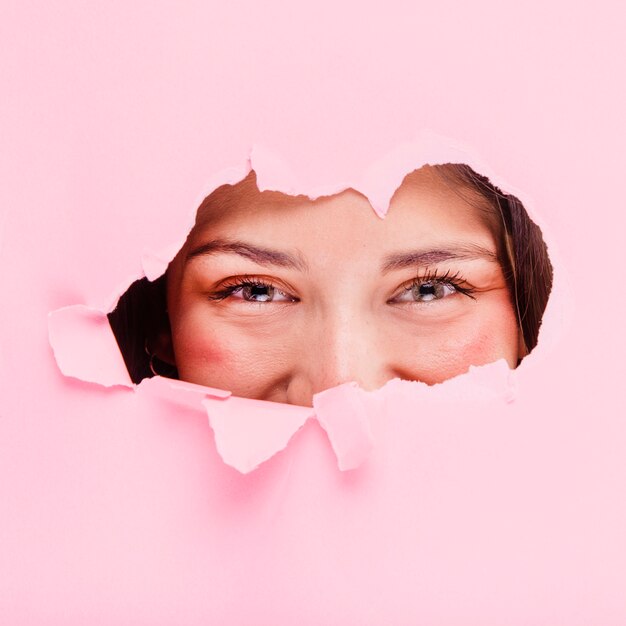 Brunette girl posing through a paper hole