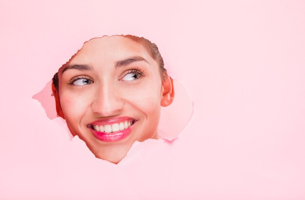 Brunette girl posing through a paper hole