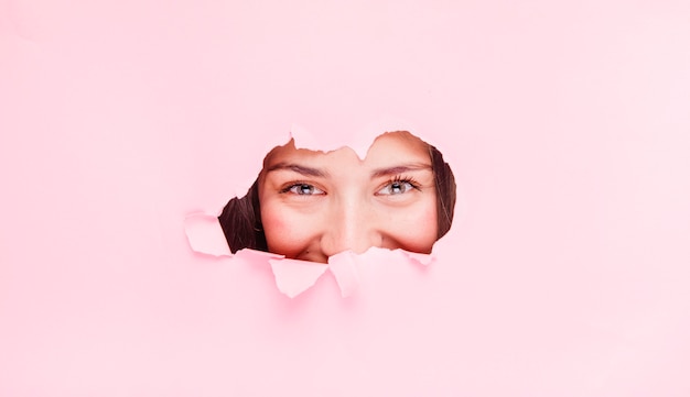 Free photo brunette girl posing through a paper hole