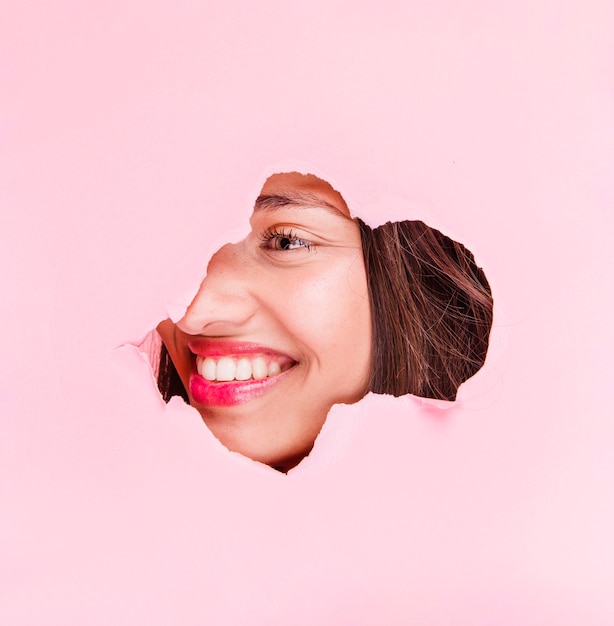 Brunette girl posing through a paper hole