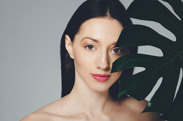 Brunette girl posing with exotic leaves