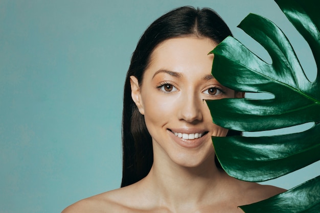 Brunette girl posing with exotic leaves