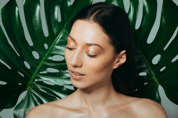 Brunette girl posing with exotic leaves