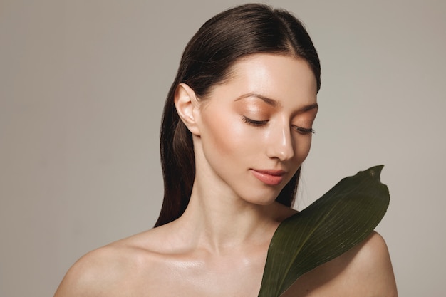 Brunette girl posing with exotic leaves