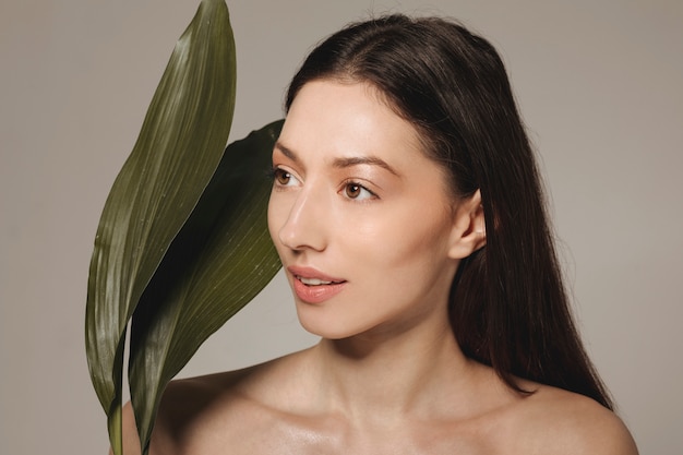 Brunette girl posing with exotic leaves