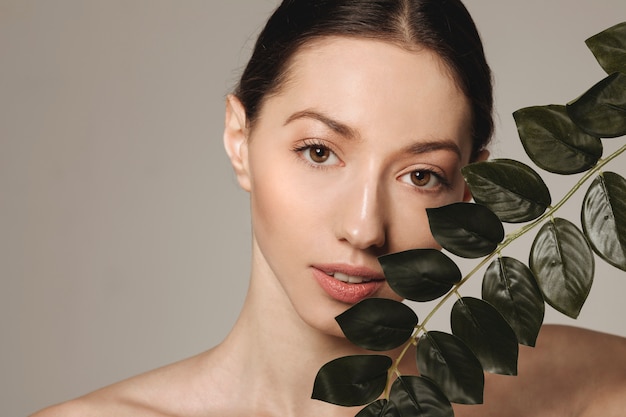 Free photo brunette girl posing with exotic leaves