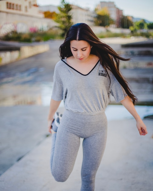 Brunette girl standing on pavement stretching