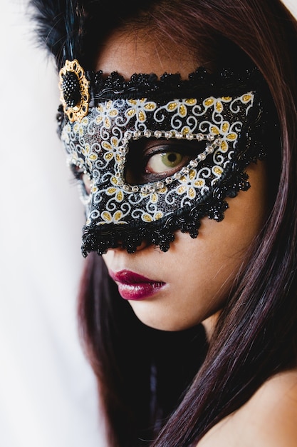 Free photo brunette girl with a white venetian mask