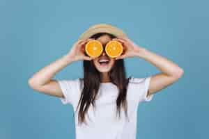 Free photo brunette girl in yellow skirt holds oranges before her eyes and smiles