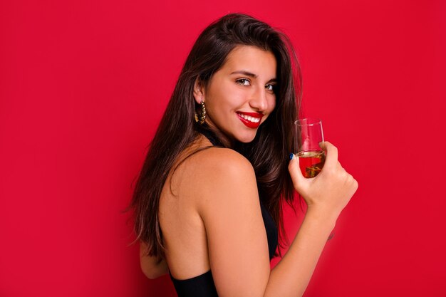 Brunette happy girl smiling to camera with a glass of champagne.