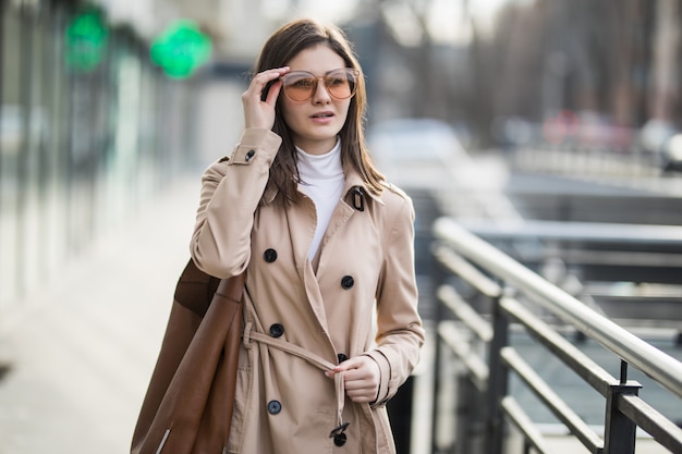 Brunette model in transperent sunglasses walk outside in autumn day