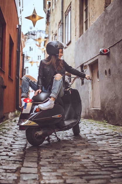 Brunette sexy girl in sunglasses sitting on Vespa scooter.