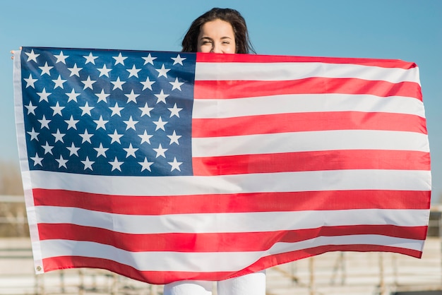 Free photo brunette woman holding big usa flag over herself