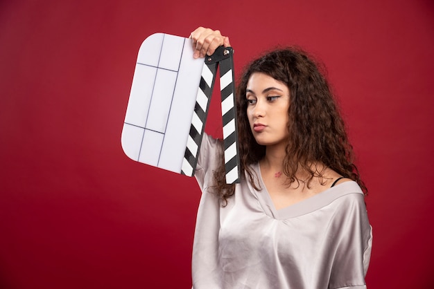 Brunette woman looking at clapperboard.